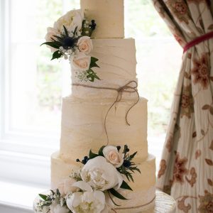 Buttercream Naked Wedding Cake with a double cascade of fresh flowers and personal Mr & Mrs Cake Topper